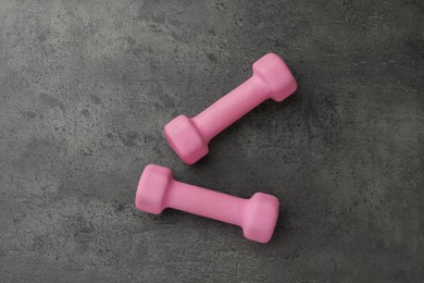 Photo of Two pink dumbbells on grey table, flat lay