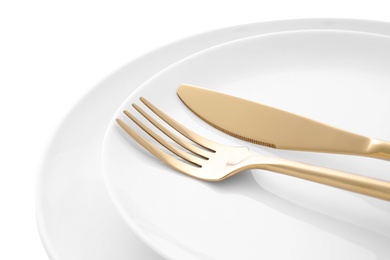Stylish shiny cutlery and plates on white background, closeup