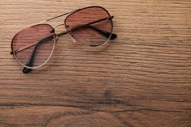 New stylish sunglasses on wooden table, top view. Space for text
