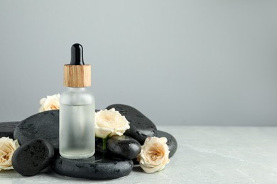 Bottle of face serum with spa stones and beautiful roses on wet table against grey background. Space for text