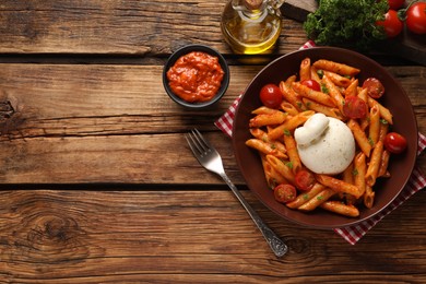 Delicious pasta with burrata cheese and tomatoes served on wooden table, flat lay. Space for text