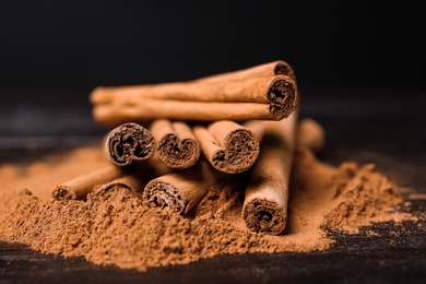 Aromatic cinnamon sticks and powder on table, closeup