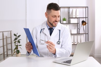 Pediatrician consulting patient online at desk in office