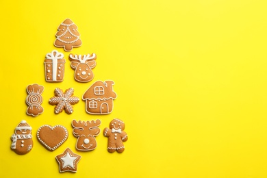 Delicious gingerbread cookies arranged in shape of Christmas tree on yellow background, flat lay. Space for text