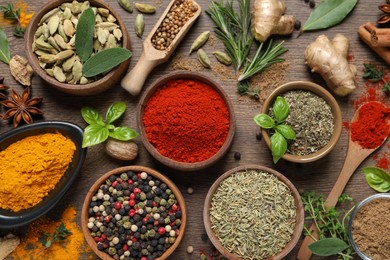 Photo of Different herbs and spices on wooden table, flat lay