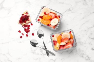 Delicious fresh fruit salad in bowls on white marble table, flat lay