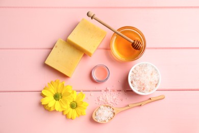 Natural beeswax, lip balm, honey, sea salt and flowers on pink wooden table, flat lay