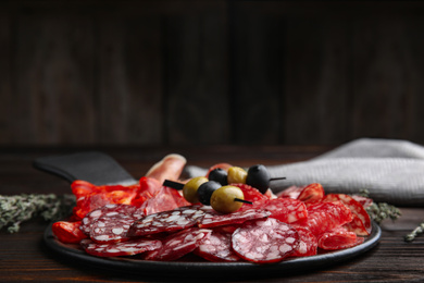 Photo of Tasty salami and other delicacies on wooden table