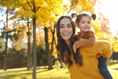 Photo of Happy woman with little daughter in sunny park. Autumn walk