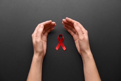 Woman with red awareness ribbon on black background, top view. World AIDS disease day