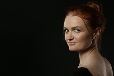 Photo of Candid portrait of happy red haired woman with charming smile on dark background, space for text