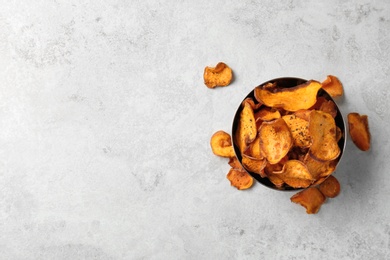 Bowl and sweet potato chips on light table, top view. Space for text