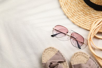 Photo of Stylish sunglasses and different beach accessories on sand, flat lay. Space for text