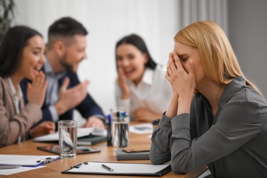 Coworkers bullying their colleague at workplace in office