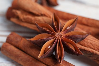 Aromatic anise star and cinnamon sticks on white wooden table, closeup
