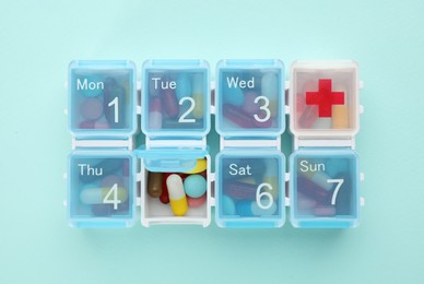 Pill box with medicaments on turquoise background, top view