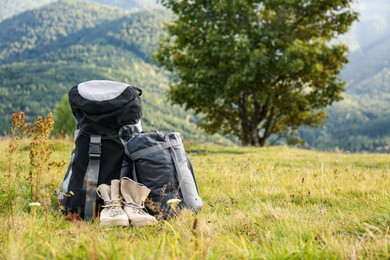 Photo of Backpack, sleeping bag and boots on lawn, space for text. Tourism equipment
