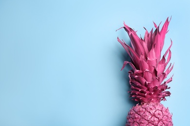 Photo of Top view of painted pink pineapple on light blue background, space for text. Creative concept