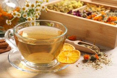 Freshly brewed tea and dried herbs on white wooden table, closeup