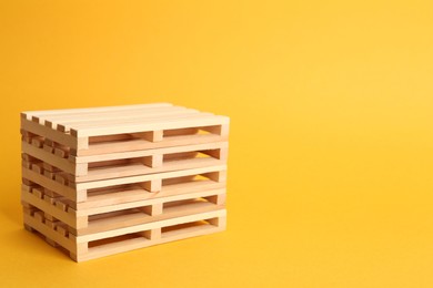 Stack of wooden pallets on orange background, space for text