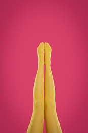 Woman wearing yellow tights on crimson background, closeup of legs