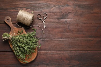 Bunch of aromatic thyme, scissors and twine on wooden table, flat lay. Space for text