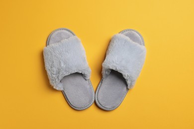 Pair of soft fluffy slippers on yellow background, top view