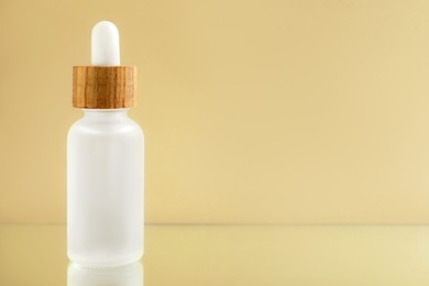 Bottle of face serum on beige background, closeup. Space for text