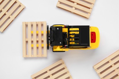 Toy forklift and wooden pallets on white background, top view