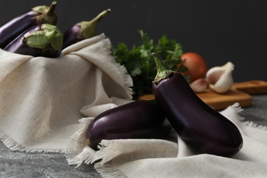 Ripe purple eggplants and napkin on grey table