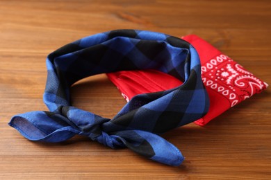 Tied and folded bandanas with different patterns on wooden table