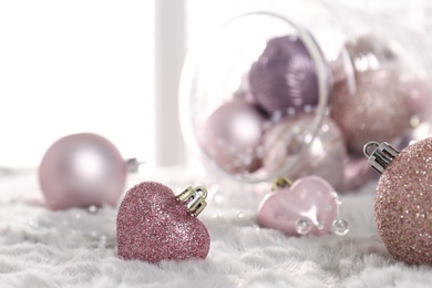 Beautiful pink Christmas baubles on white fur. Space for text
