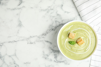 Delicious broccoli cream soup with croutons served on white marble table, top view. Space for text