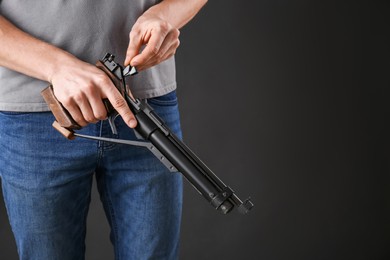 Gun shooting sport. Man holding standard pistol on dark background, closeup. space for text