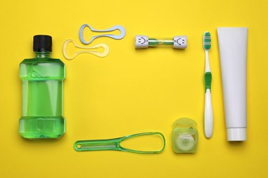 Flat lay composition with tongue cleaners and teeth care products on yellow background. Space for text