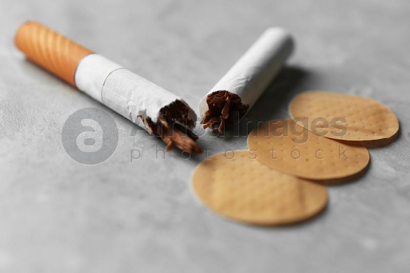Nicotine patches and broken cigarettes on grey table, closeup