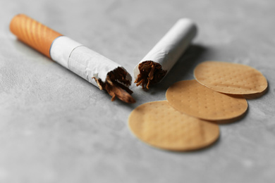 Nicotine patches and broken cigarettes on grey table, closeup