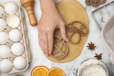 Woman making biscuits with cookie cutters on white marble table, top view