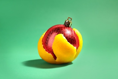 Photo of Christmas ball in tangerine zest on green background