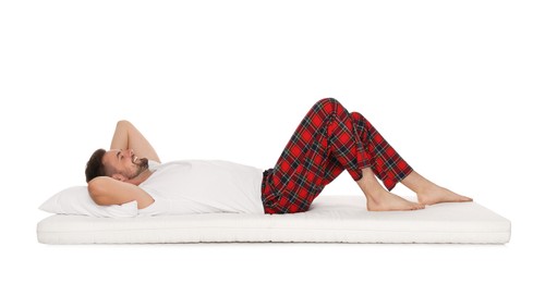 Photo of Smiling man lying on soft mattress against white background