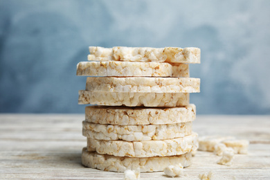 Stack of puffed rice cakes on white wooden table against light blue background