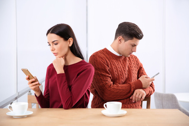 Couple addicted to smartphones ignoring each other in cafe. Relationship problems