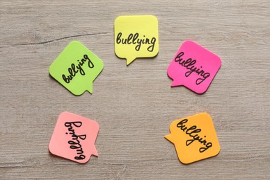 Stickers with word Bullying on wooden table, flat lay