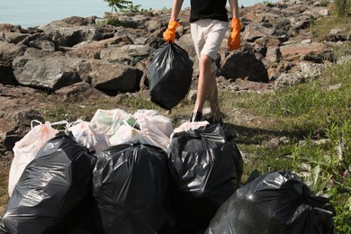 Man with trash bag full of garbage in nature, closeup. Environmental Pollution concept