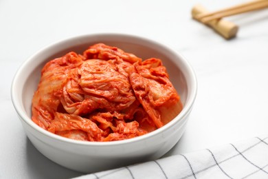 Photo of Bowl of spicy cabbage kimchi on white marble table