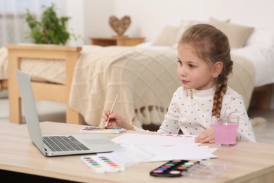Photo of Little girl learning to paint with online course at home. Space for text