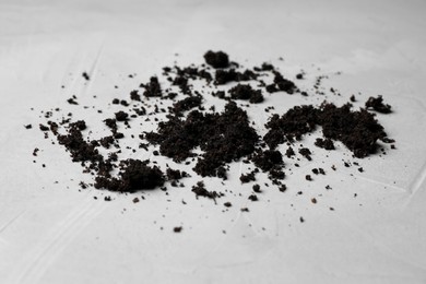 Scattered coffee grounds on light surface, closeup