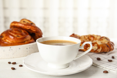 Cup of coffee and fresh tasty pastries on white wooden table