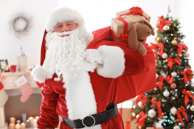 Authentic Santa Claus with bag of gifts indoors
