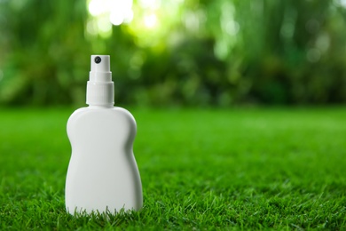 Bottle of insect repellent spray on green grass. Space for text